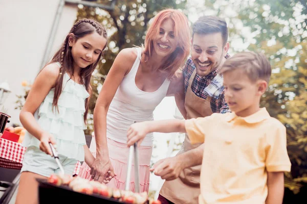 晴れた日に庭で昼食のバーベキューを持つ幸せな若い家族 — ストック写真