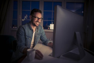 Karanlık odada bilgisayarda çalışan genç adam