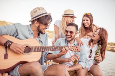 Sahilde gitar çalmak ve soğuk bira içmek arkadaşlar