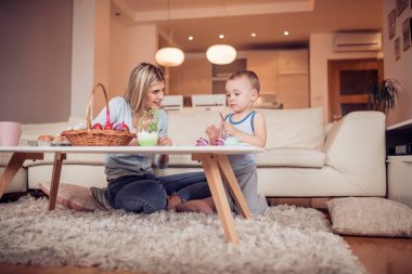 Genç anne oğluyla Paskalya yumurtaları oturma odasında boyama