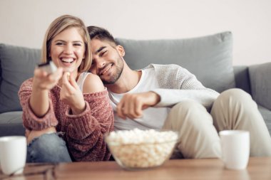Genç çift oturma kanepe evde patlamış mısır ile yakın ve Tv izlerken