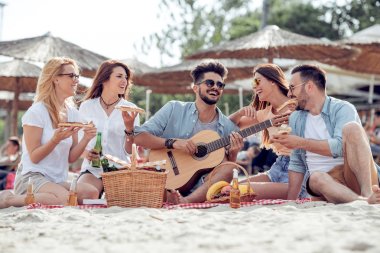 Kumsalda eğleniyor ve soğuk bira içmek arkadaşlar