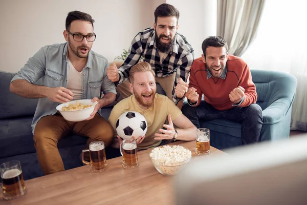 Group of friends-football fans watching soccer game on television and celebrating goal