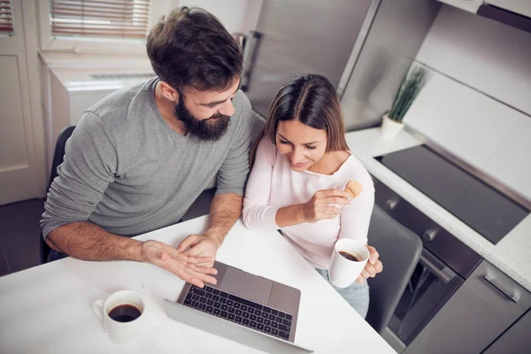 Cheerful couple surfing in laptop at home