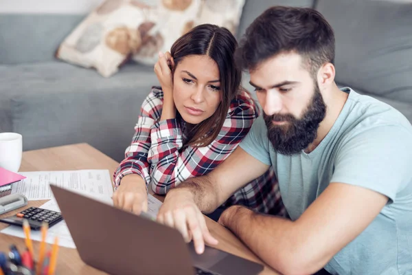 Pareja Joven Comprobando Facturas Con Ordenador Portátil Casa —  Fotos de Stock