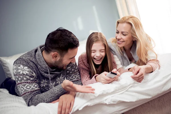 Family watching TV in bedroom and laughing