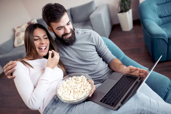 陽気なカップルはポップコーンを食べるとリビング ルームで映画を見て — ストック写真