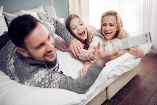 Family watching TV in bedroom and laughing