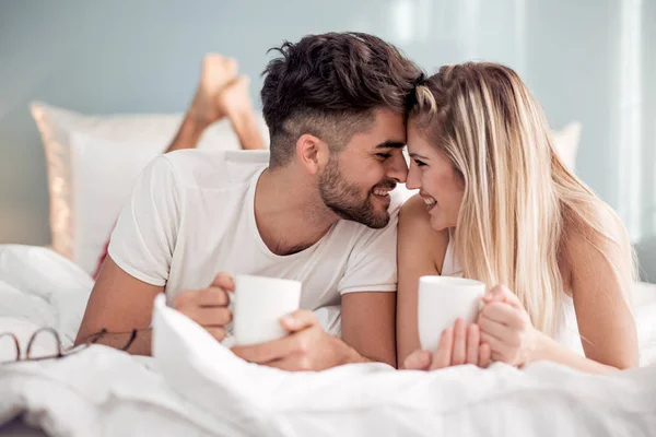 Young couple drinking coffee in bed at morning