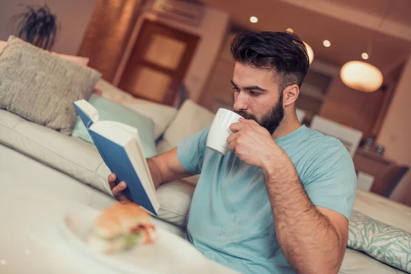 Young Man Sitting Sofa Reading Book Drinking Cup Coffee — Stock Photo, Image