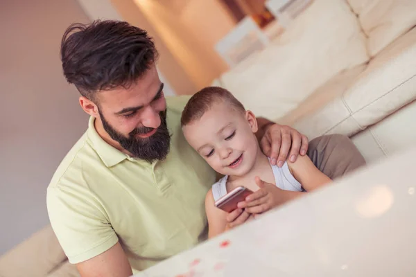 Joven Padre Enseñando Hijo Pequeño Usando Teléfono Inteligente Casa — Foto de Stock