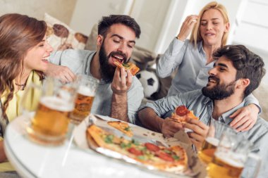 Pizza yiyip evde bira içmeyi gülümseyen arkadaşlar