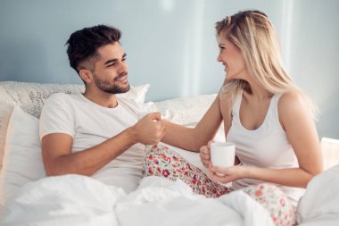 Genç çift yatakta kahve içme pijama