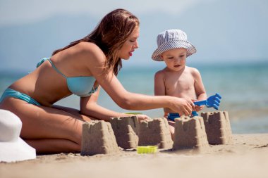 Rock tarafından deniz plaj kenarında oturan kadın. Yaz tatili.