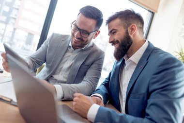 Kentsel kafede masada oturan ve dizüstü bilgisayar kullanarak iki iş adamları