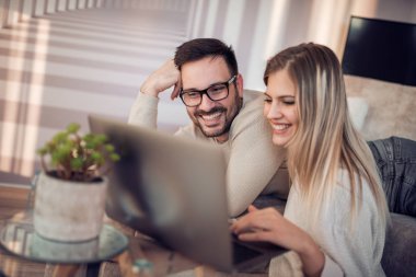 Genç çift kanepede dizüstü bilgisayar ile rahatlatıcı