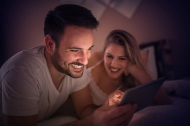 Genç çift tablet bilgisayar ile yatak odasında rahatlatıcı