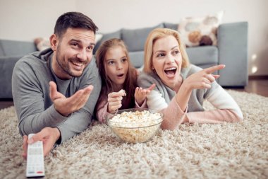 Baba, mather ve yerde yatarken, Tv izlerken ve patlamış mısır yemek kız