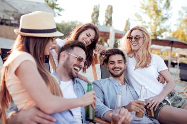 Grup gülümseyen arkadaşıyla sahilde bira şişesi tungur.
