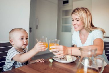 Kek yiyip anne ile portakal suyu içmeyi küçük çocuk.