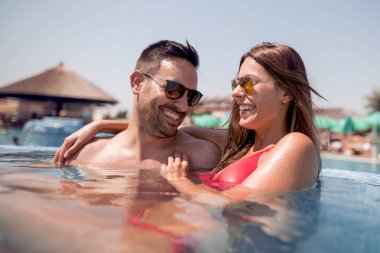 Mutlu genç çift rahatlatıcı ve huging yüzme havuzunda.