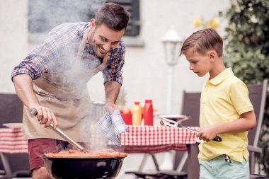 Oğlu ile pişirme barbekü ızgara et adam