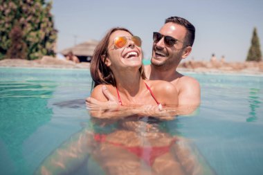 Mutlu genç çift rahatlatıcı ve huging yüzme havuzunda.