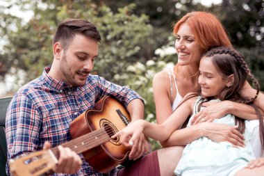 Mutlu baba gitar, anne ve kızı şarkı şarkı yürütme.
