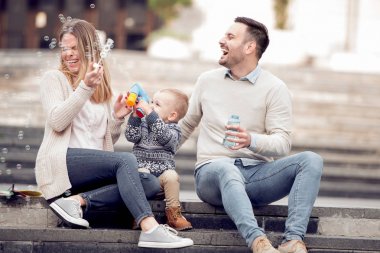 Kabarcıklar üfleme ve having fun şehirde mutlu genç aile