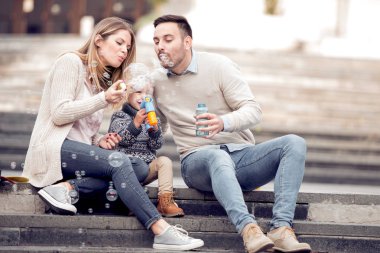 Kabarcıklar üfleme ve having fun şehirde mutlu genç aile