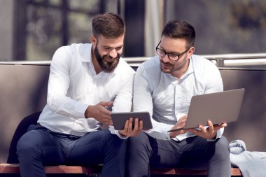  Dizüstü ve tablet bakarak iki emin işadamları yaparken break açık havada.