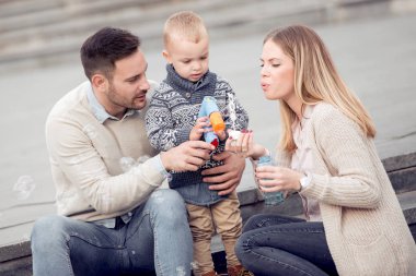Kabarcıklar üfleme ve having fun şehirde mutlu genç aile