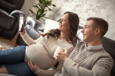 Hamile kadın kocasıyla evde dinlenirken Smartphone kullanarak.