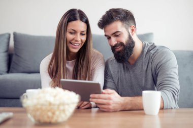 Mutlu çift sabah kahve tadını çıkarırken tablet üzerinde sörf.