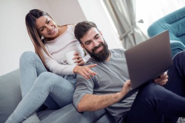 Genç çift ile laptop evde oturma odasında kanepede rahatlatıcı.
