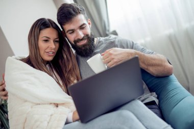 Genç çift ile laptop evde oturma odasında kanepede rahatlatıcı.