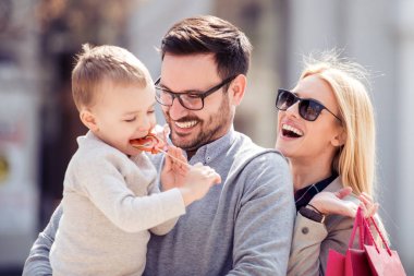 Mutlu bir genç aile küçük oğlu ve City, alışveriş torbaları ile birlikte eğleniyor.