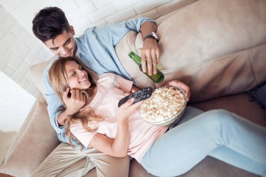 Genç çift dairelerinde rahatlatıcı, kanepede yatan, bir film seyrederken ve patlamış mısır yemek.