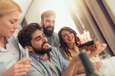 Doğum günü pastası partide arkadaşlarıyla çevrili mum üzerinde üfleme adam portresi.