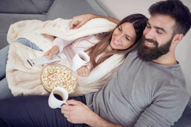 Evde patlamış mısır ile kanepede oturan ve Tv izlerken mutlu genç Çift.