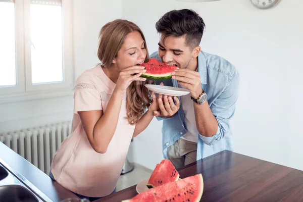 Couple eating in the kitchen, preparing healthy food,they are eat fresh fruits.