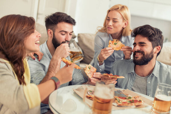 Friends having fun at home,eating pizza and drink some cold beer.