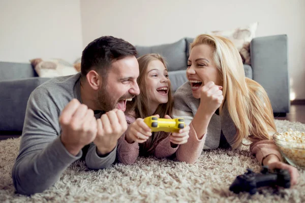 Family of three lying on the floor and enjoying playing video games.
