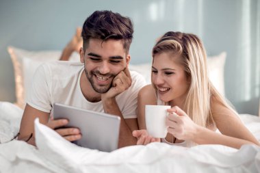 Mutlu çift aşık evde pijamayla tablet kullanma.