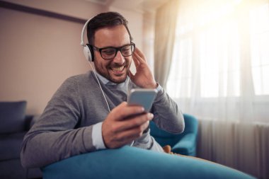 Kulaklıklar ile mutlu genç adam. Evde müzik.