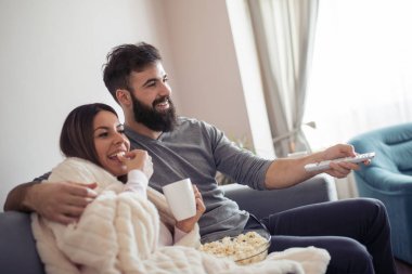 -Kanepede televizyon izlerken mutlu çift aile, boş zaman, beraberlik, eğlence ve yaşam tarzı kavramı.