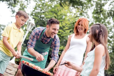 Mutlu genç aile Barbekü yapma. Eğlence, gıda, insanlar ve tatil kavramı.