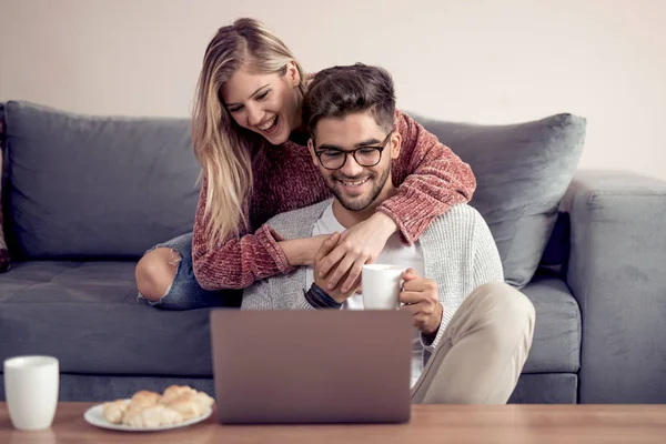 Güzel Genç Çift Evde Kanepede Otururken Gülümseyen Dizüstü Bilgisayar Kullanarak — Stok fotoğraf