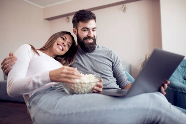 幸せな若いカップル ポップコーンを自宅のソファーに座って ノート パソコンに映画を見て — ストック写真