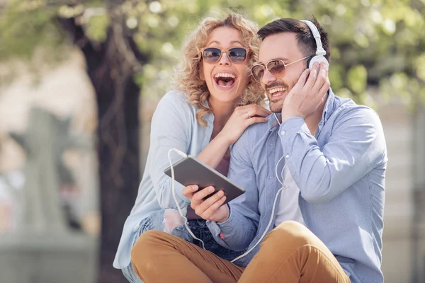 Couple listening to music together while sitting in a city park.People,love,music and happiness concept.